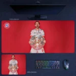 Harry Kane Bayern Trophy Moment Desk Mat featuring Kane holding silverware against a bold Bayern red background