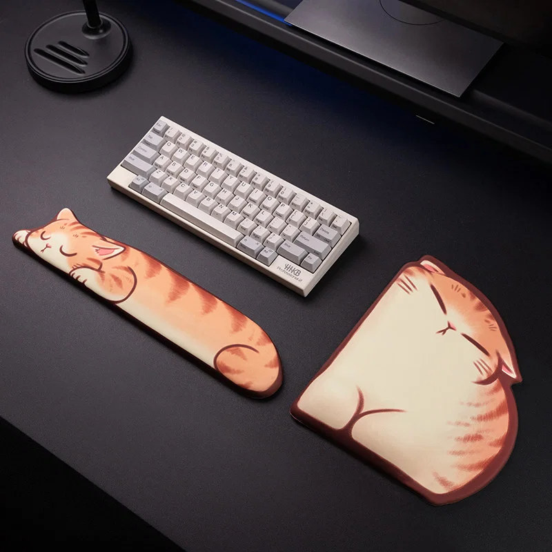 Sleepy Orange Tabby Wrist Rest Collection laid out on a black desktop, showing the matching cat keyboard wrist rest and wrist-rest mouse pad next to a compact keyboard.