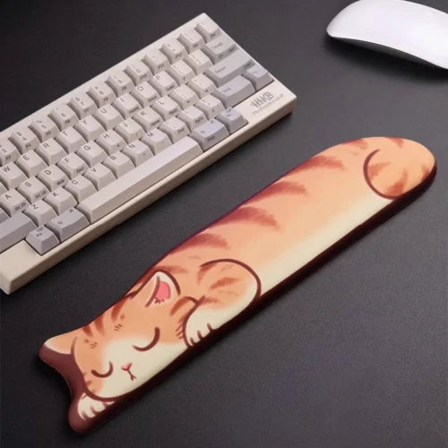 Sleepy Orange Tabby Keyboard Wrist Rest beside a compact keyboard on a dark desktop, long padded cat design for wrist cushioning while typing.