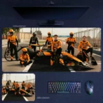 Lando Norris 2025 team edition desk mat with McLaren crew portrait, pit lane lineup, and championship-era F1 team atmosphere