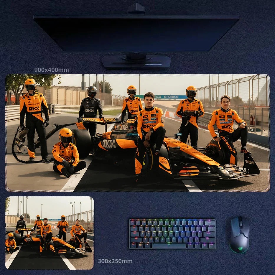 Lando Norris 2025 team edition desk mat with McLaren crew portrait, pit lane lineup, and championship-era F1 team atmosphere
