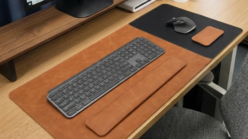 Executive Leather Desk Pad and Wrist Rest Set shown on a wooden office desk with keyboard, mouse area, and matching wrist rests