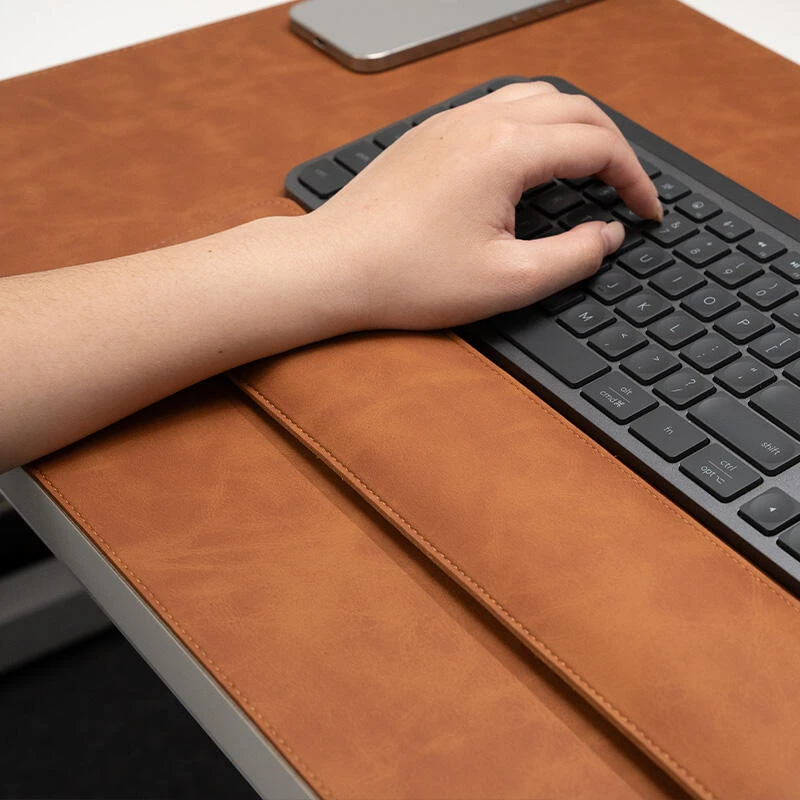 Close-up of the leather keyboard wrist support paired with the executive desk pad, showing surface texture and front-edge placement