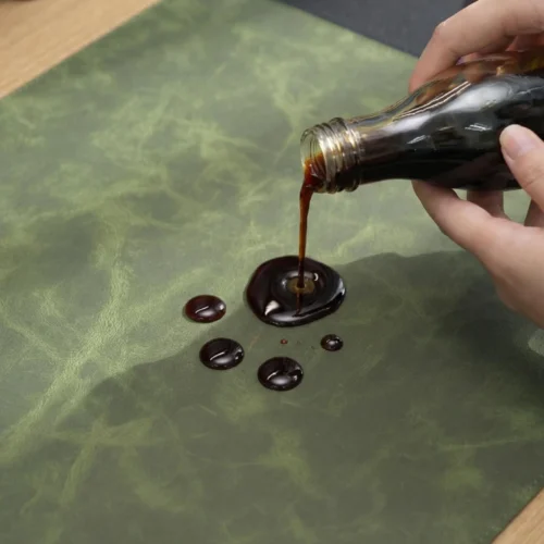 Dark liquid on the green leather section of the executive desk mat demonstrating an easier-clean surface for maintaining a tidy office desk