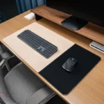 Cream leather desk mat with a black fabric mouse area shown in a clean office desktop setup with keyboard on the left side