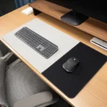 Light gray executive leather desk mat with black fabric mouse area positioned on a modern office desk with keyboard and mouse