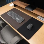 Dark brown leather desk mat with a black fabric mouse area shown in a professional workspace with keyboard and mouse