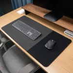 Charcoal executive leather desk mat with a black fabric mouse area in a minimalist office setup with keyboard on the left section