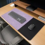 Lavender executive leather desk mat with a black fabric mouse section arranged in a neat office desktop setup with keyboard and mouse