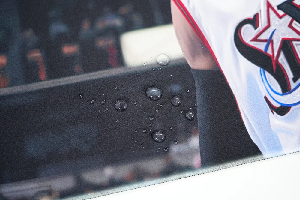 Close-up of water droplets on a spill-resistant basketball mouse mat surface, showing liquid beading above the printed fabric