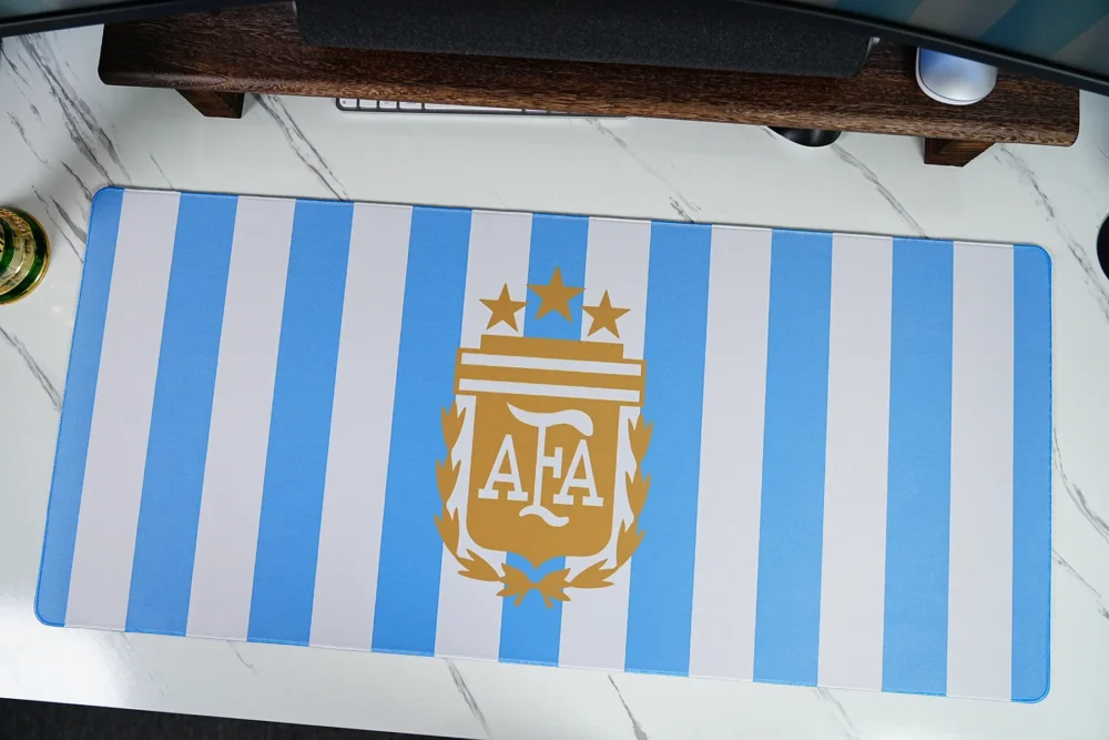 Argentina Blue White Football Desk Mat Blue-white Argentina football desk mat fully laid out with gold crest-style artwork, rounded corners, stitched edges, and wide desk coverage