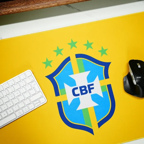 Brazil football mouse pad close-up showing vivid yellow fabric, clear crest artwork, keyboard placement, and smooth mouse space