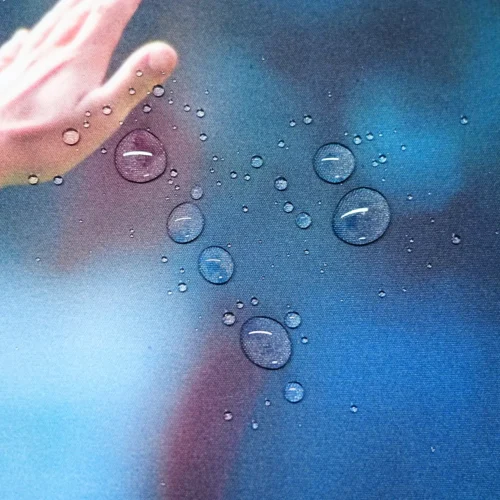Water droplets resting on the David Beckham desk mat surface, showing a spill-resistant fabric that keeps small liquid spills on the surface for easier cleanup