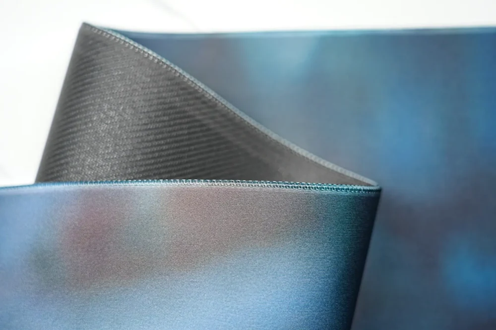 David Beckham desk mat lifted to show the flexible rubber base, revealing a bendable structure that supports easy storage, repositioning, and stable desktop placement