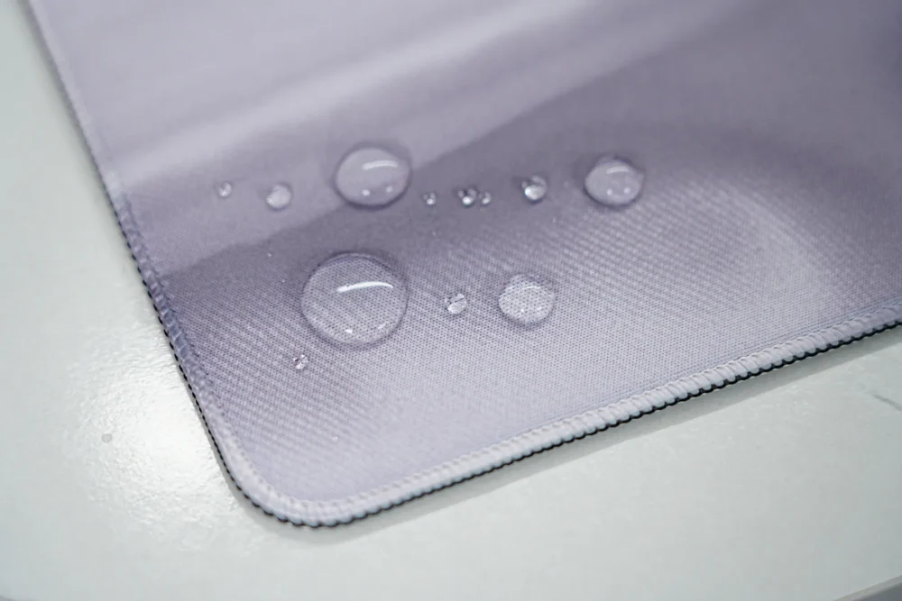 Spill-resistant England desk mat surface with water droplets staying on top to reduce soaking, stains, and interrupted mouse use