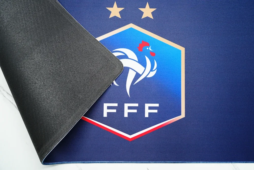 Anti-Slip Rubber France Football Desk Mat France football desk mat lifted to show textured rubber backing, flexible body, and stitched edge for stable desk placement