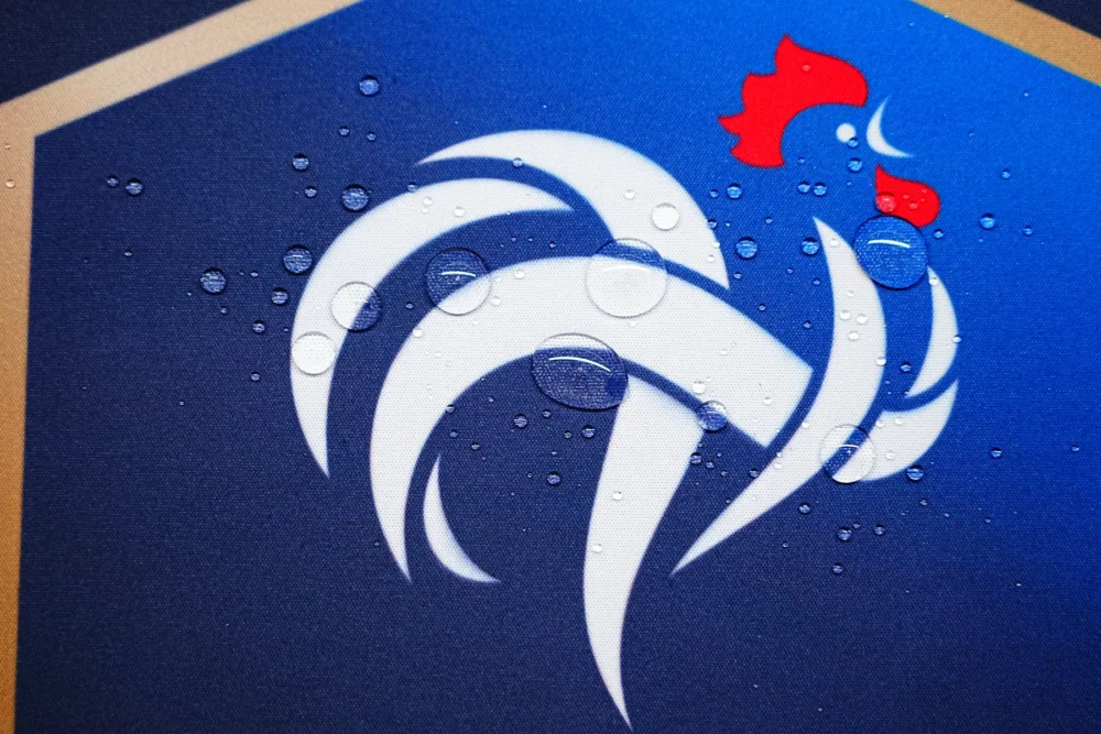 Spill-Resistant France Football Desk Mat Water drops bead on the France football desk mat surface, showing spill-resistant fabric that keeps the crest area usable