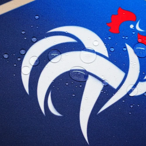 Spill-Resistant France Football Desk Mat Water drops bead on the France football desk mat surface, showing spill-resistant fabric that keeps the crest area usable