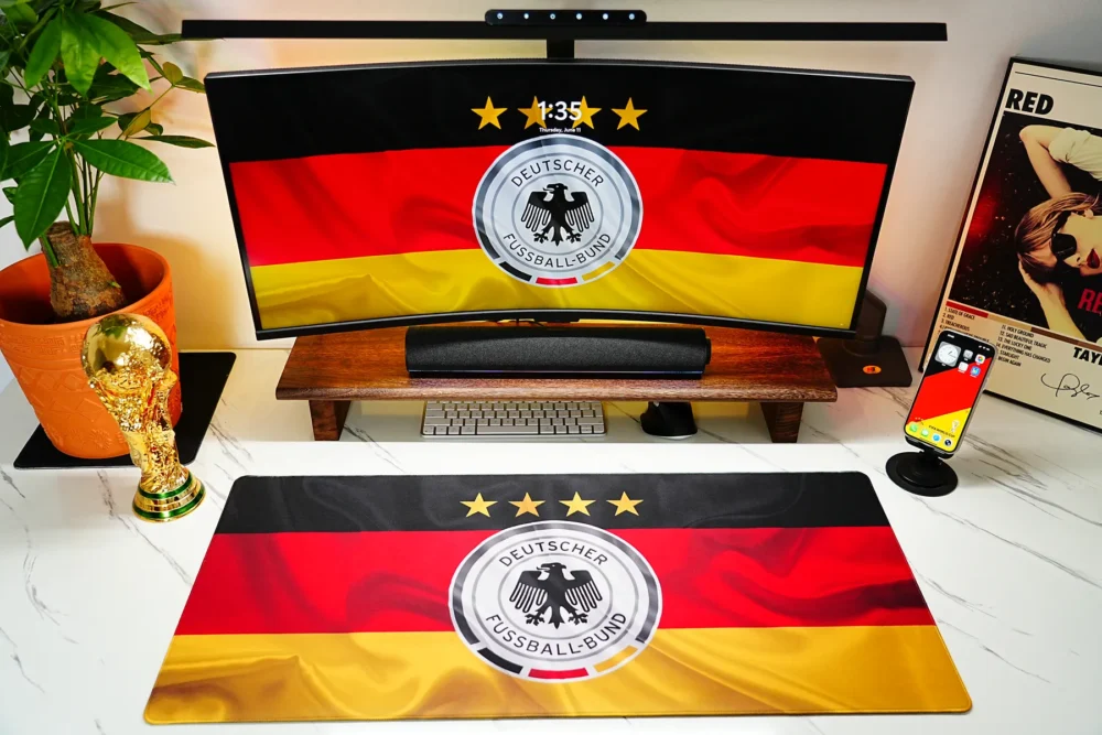 Germany Football Team Desk Mat shown in a full fan desk setup with matching monitor wallpaper, World Cup trophy decor, and football-themed workspace