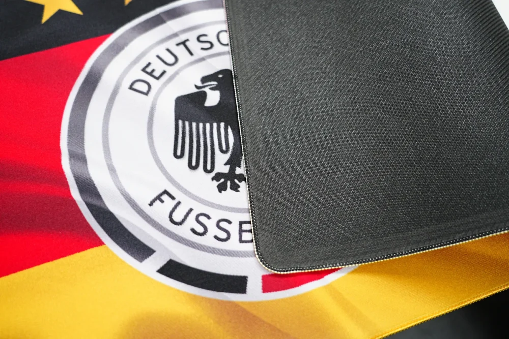 Germany football desk mat flipped to show black anti-slip rubber base and printed fabric surface comparison