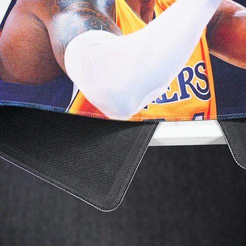 Kobe Bryant mouse pad lifted to show anti-slip rubber base, stitched edges, and flexible desk mat structure