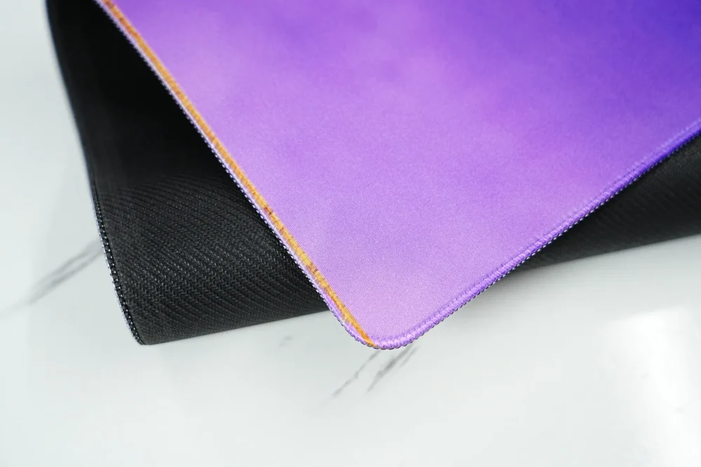 Stitched Edge LeBron Desk Mat Rubber Base LeBron desk mat corner lifted to show stitched edges, fabric surface, and anti-slip rubber base for stable use