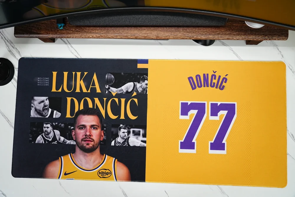 Top view of a Lakers 77 basketball desk pad showing the full Luka-inspired artwork, wide surface, stitched border, and desk fit