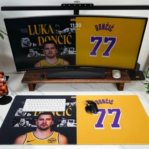 Lakers 77 fan gaming desk mat shown in a styled workspace with monitor, keyboard, mouse, plants, and basketball-inspired decor