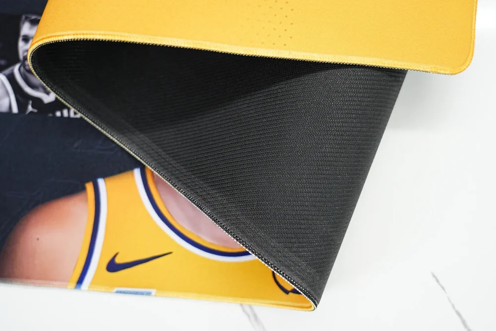 Close-up of the desk pad underside showing textured anti-slip rubber base and stitched edge for better grip and durability