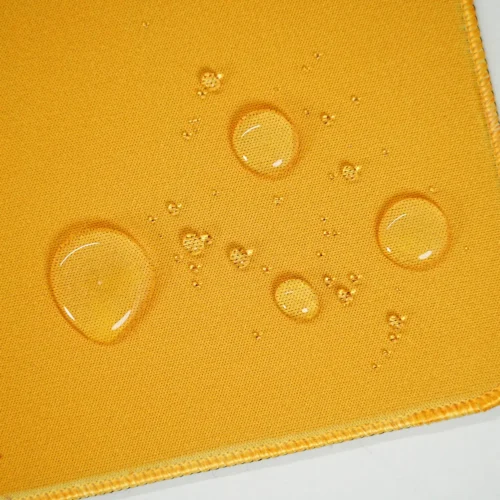 Water drops resting on the desk pad surface, showing water-resistant fabric that helps protect the artwork during small spills