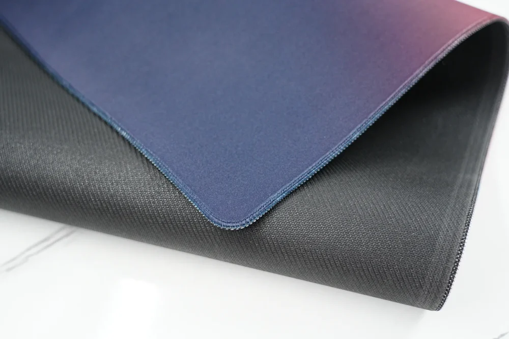 Bent gaming mouse pad showing 4mm rubber base, anti-slip texture, stitched edge, and flexible construction