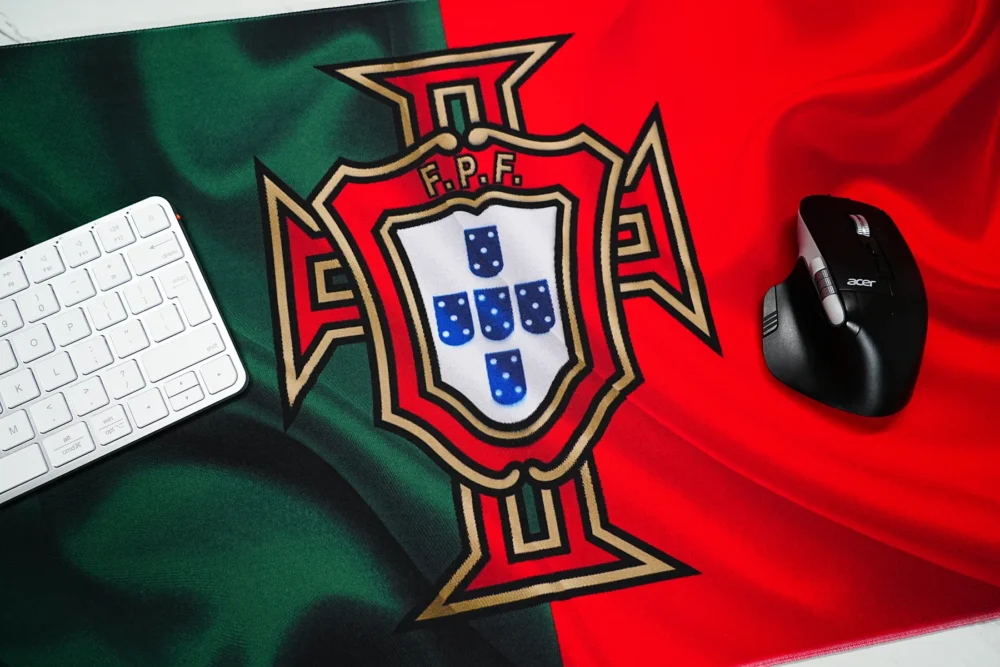 Portugal football desk mat with mouse on low-friction surface beside a keyboard for smooth movement and controlled cursor use