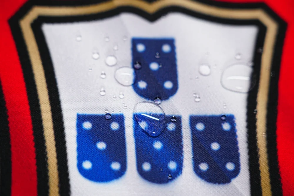 Spill-resistant Portugal football desk mat with water droplets staying on the surface to protect artwork and daily mouse use