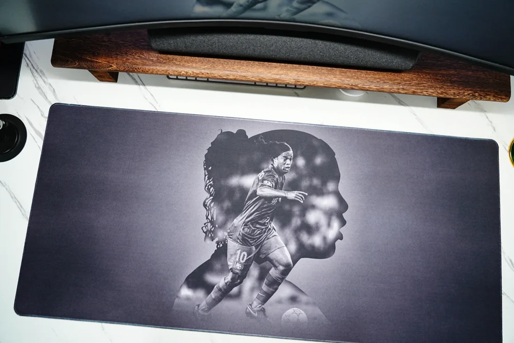 Wide Ronaldinho Barcelona desk mat placed under a monitor setup, giving fans broad desk coverage for keyboard and mouse use