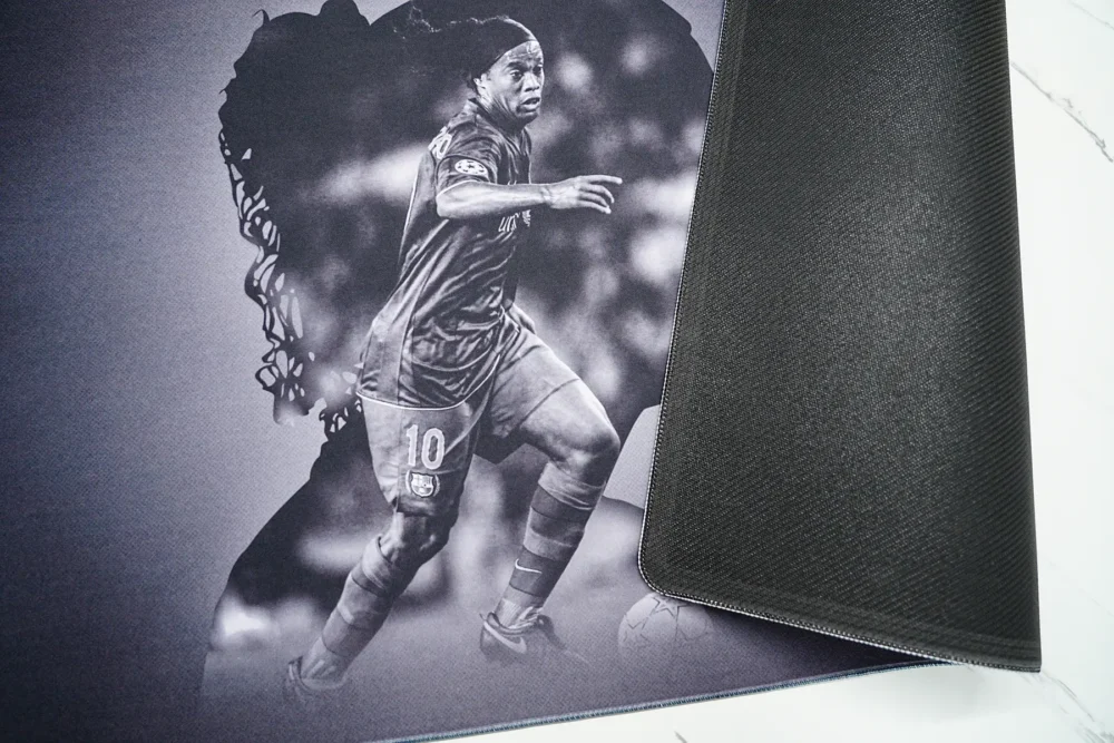 Ronaldinho Barcelona desk mat lifted to show the anti-slip rubber base and stitched edge for stable placement and edge protection