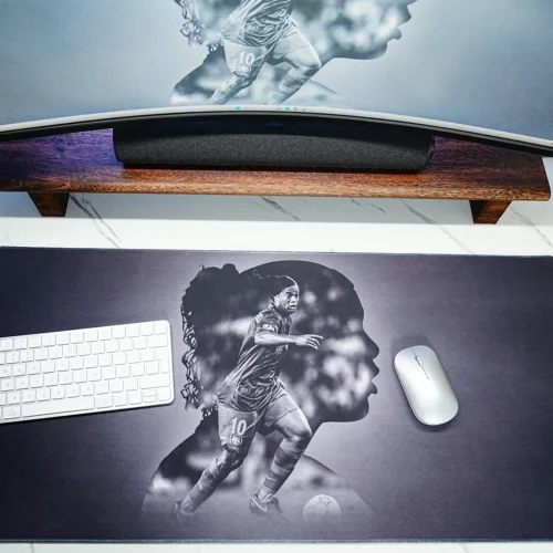 Ronaldinho Barcelona desk mat used with keyboard, mouse, matching monitor wallpaper, and World Cup trophy decor in a fan desk setup