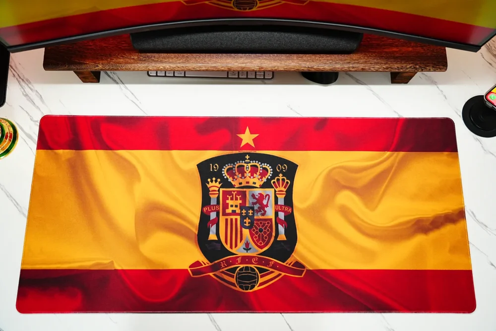 Spain football desk mat laid flat under the monitor, showing wide surface coverage that keeps keyboard and mouse areas organized.
