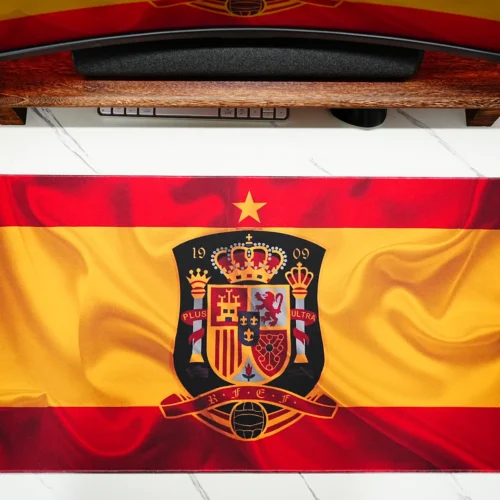 Spain football desk mat laid flat under the monitor, showing wide surface coverage that keeps keyboard and mouse areas organized.