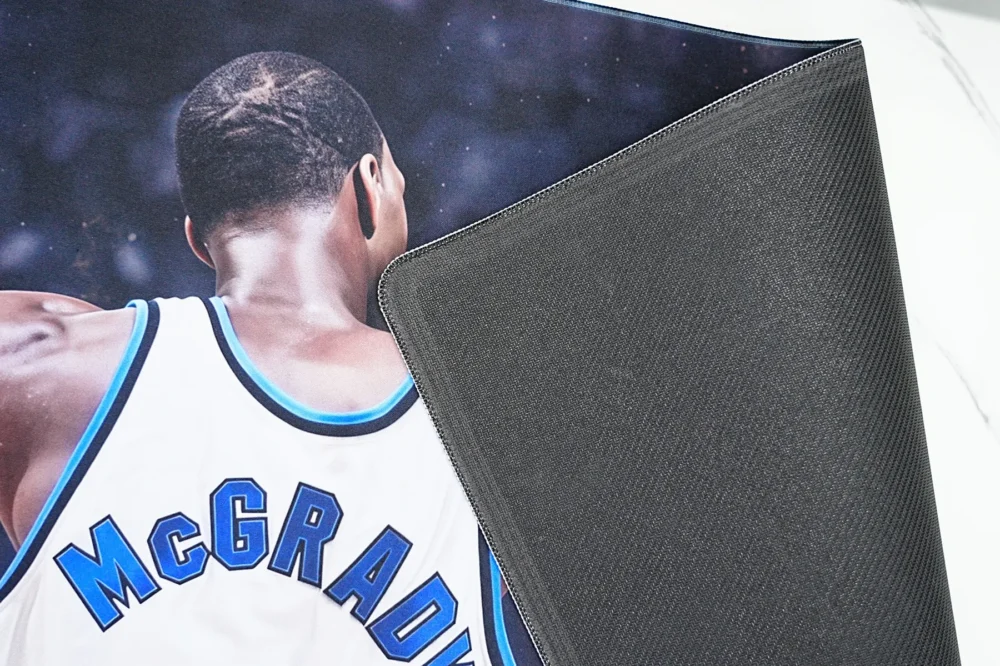 Gaming mouse pad lifted to show 4mm textured rubber base that helps grip the desk during quick mouse movement