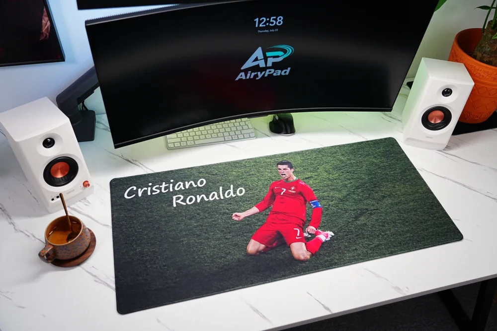 Cristiano Ronaldo desk mat in a white workstation with curved monitor, compact keyboard, mouse, speakers and coffee cup