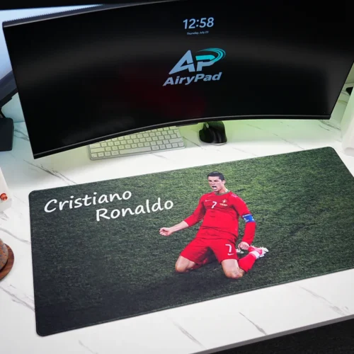 Cristiano Ronaldo desk mat in a white workstation with curved monitor, compact keyboard, mouse, speakers and coffee cup