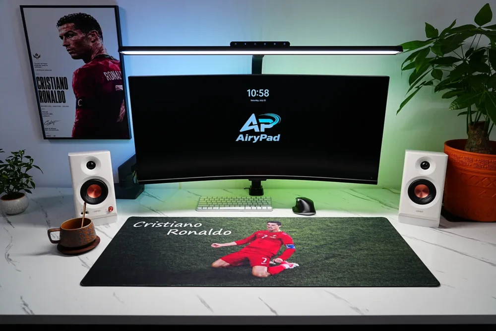 Cristiano Ronaldo football desk mat in a complete green-lit setup with curved monitor, speakers, plants and Ronaldo wall art