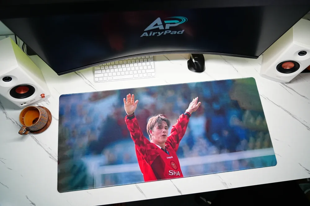 David Beckham tribute football desk mat in an angled desktop setup with a keyboard, mouse and speakers