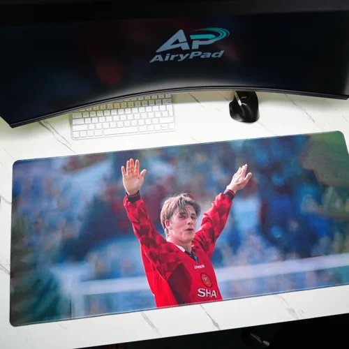David Beckham tribute football desk mat in an angled desktop setup with a keyboard, mouse and speakers
