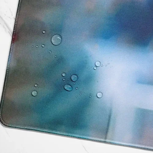 Water droplets beading on the David Beckham desk mat spill-resistant fabric beside the stitched edge