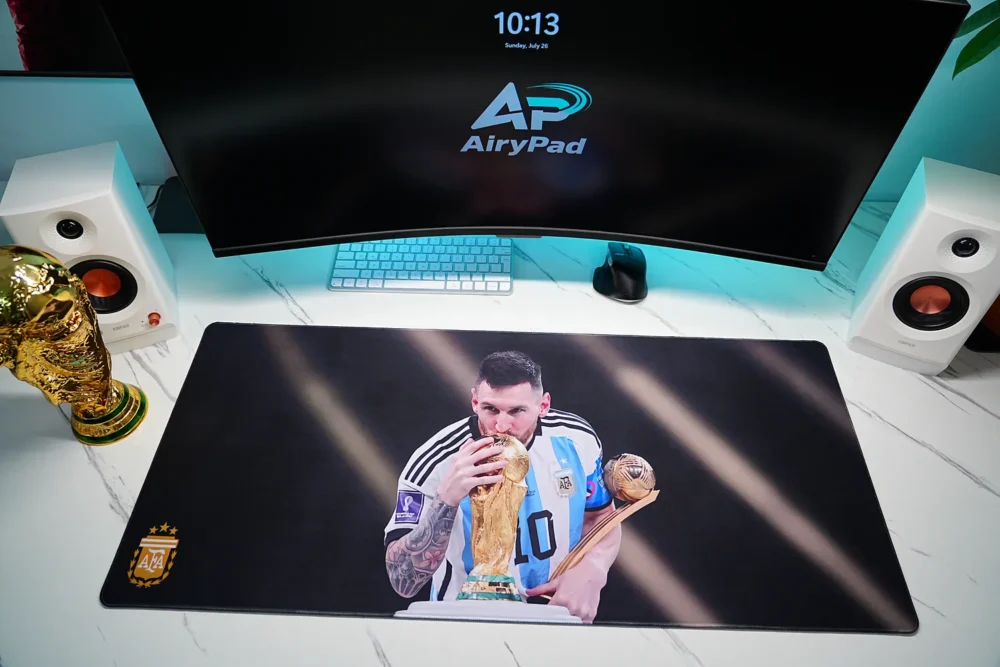 Overhead view of Lionel Messi Argentina 2022 World Cup desk mat with monitor, keyboard, mouse, speakers and trophy
