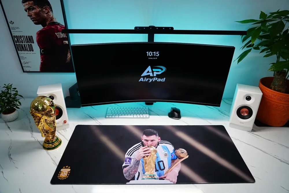 Front view of Lionel Messi Argentina World Cup desk mat in a wide desktop setup with monitor and speakers