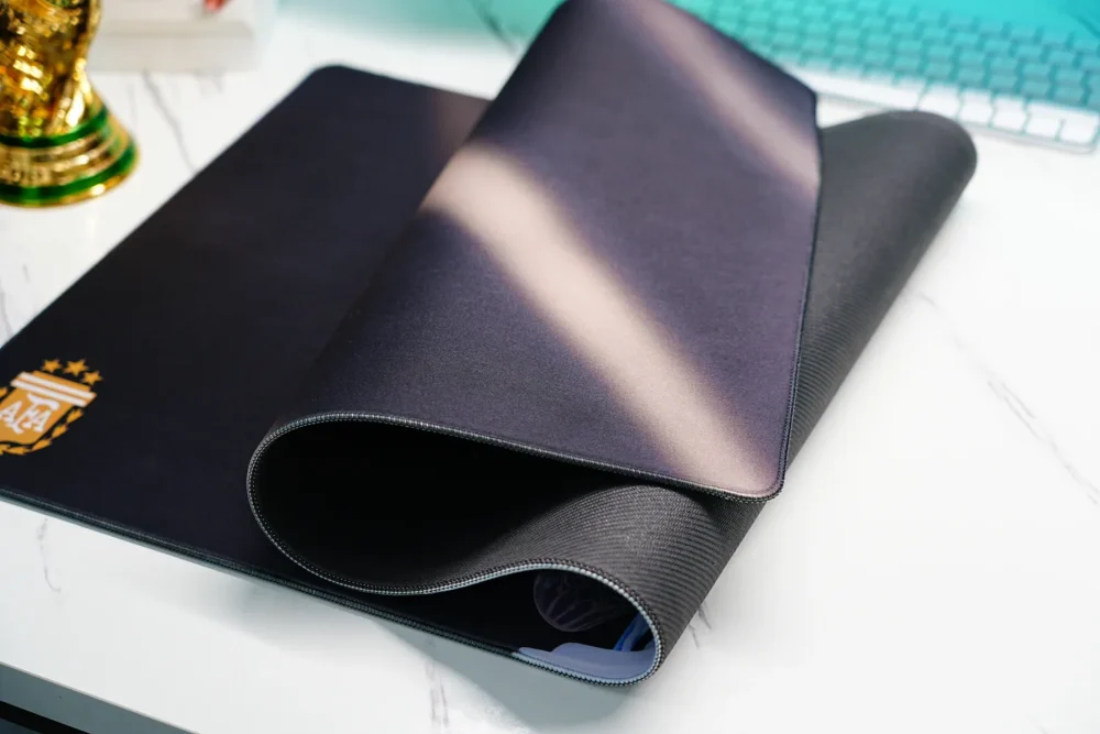 Rolled Lionel Messi World Cup desk mat showing stitched edge and textured non-slip rubber base