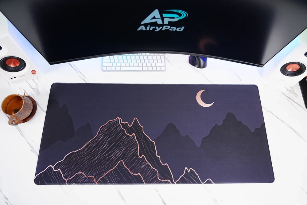 Crescent Moon Mountain desk mat under a curved monitor with keyboard and mouse