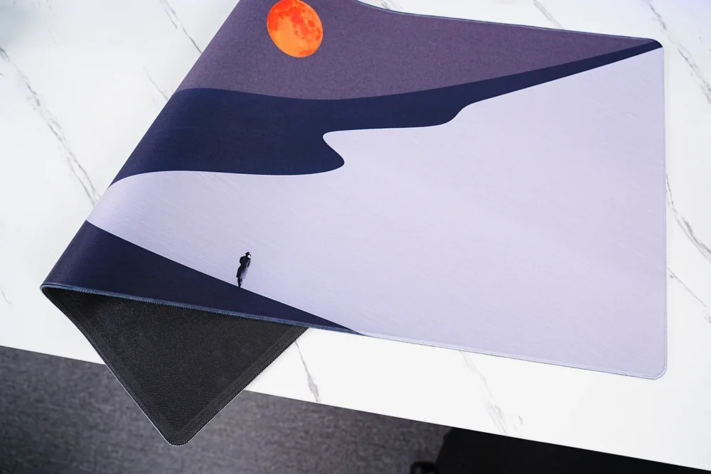 Orange Moon Desert Walker desk mat in a real desktop setup with curved monitor, keyboard and mouse